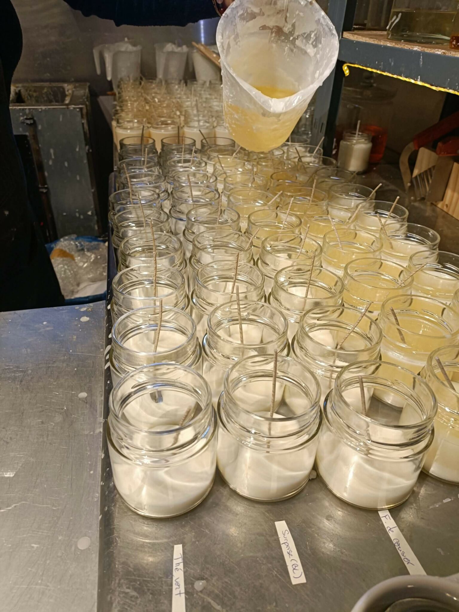 Photo du remplissage des contenants avec de la cire de soja chaude pour la fabrication de bougies artisanales.